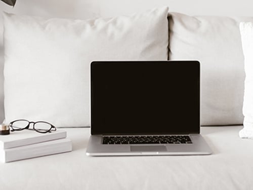Laptop And Books On Sofa Modern laptop with blank display and stack of books with glasses lying on comfortable couch in stylish room