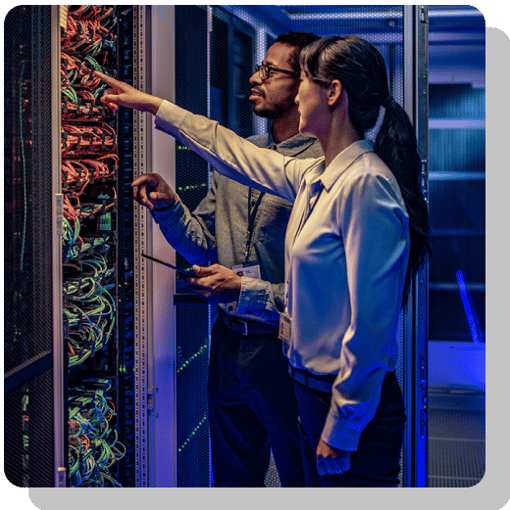 Fully-Managed SD-WAN Two IT professionals inspecting a networking panel with like a thousand wires
